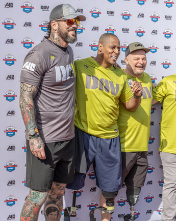 Three men posing together in front of a branded backdrop
