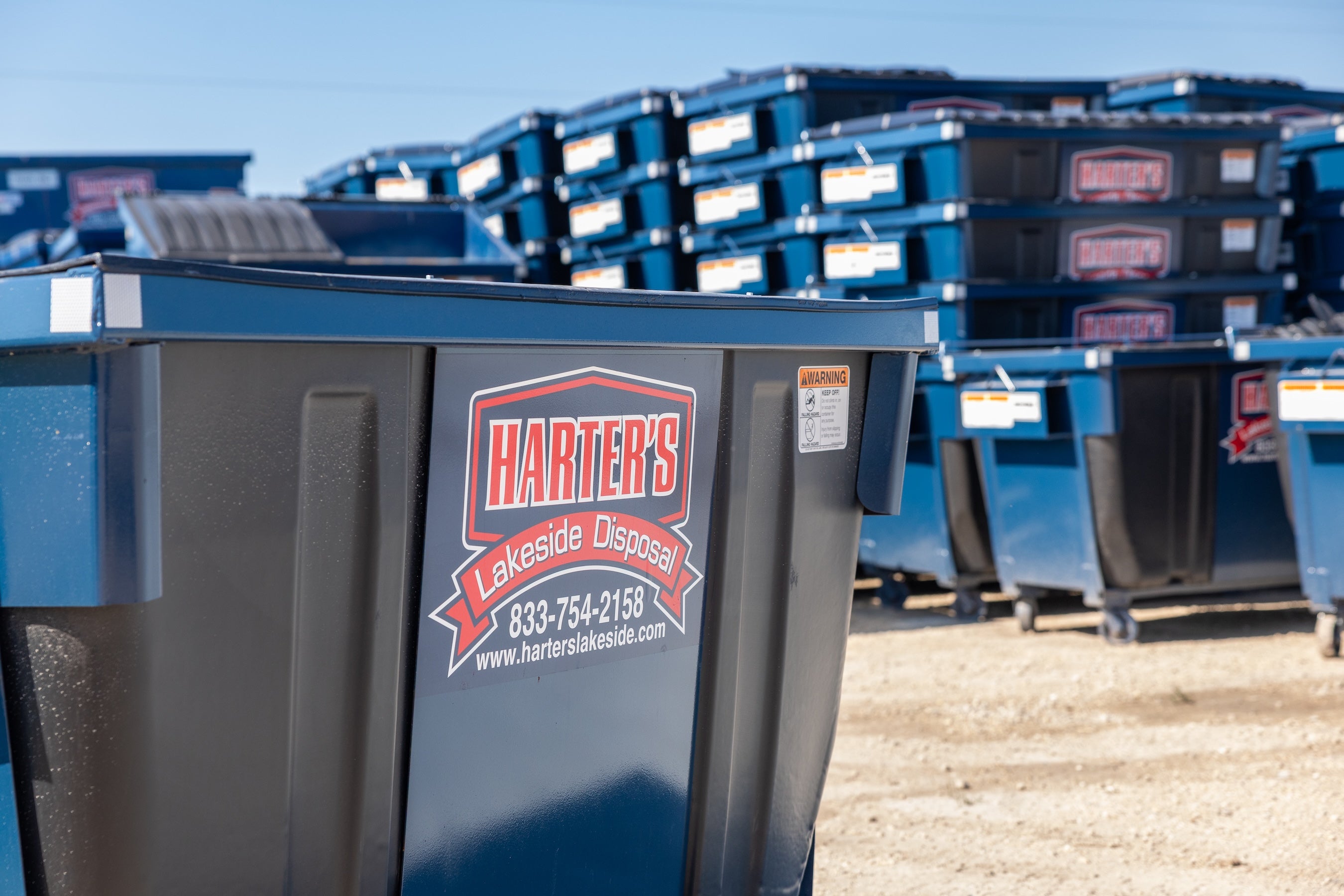 Dumpsters with Harter's Lakeside Disposal logo and contact information on a clear day.