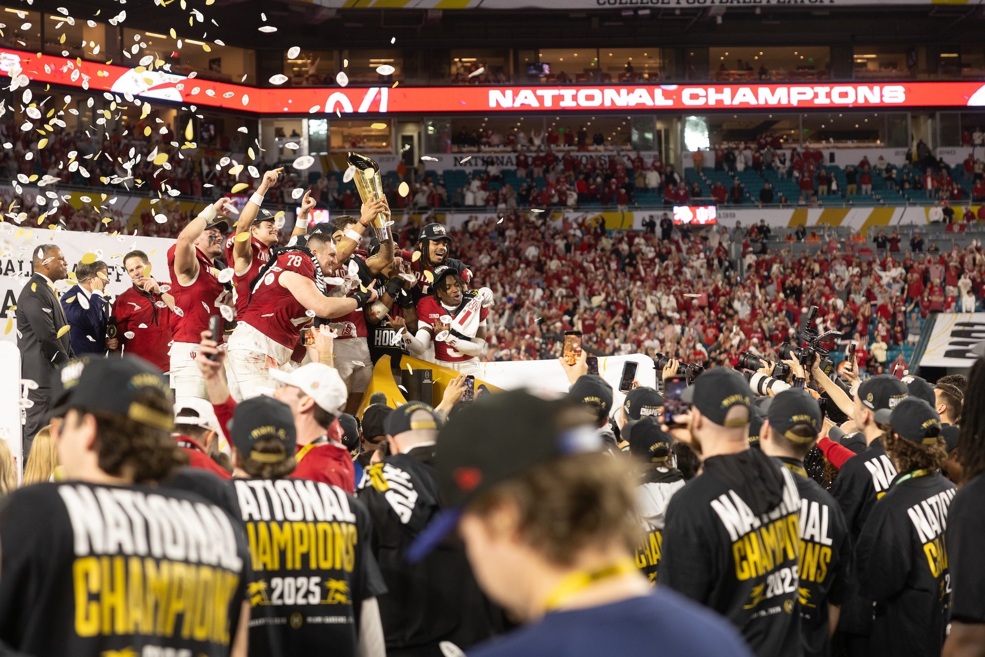 College football team celebrating on the field with 'National Champions' banner