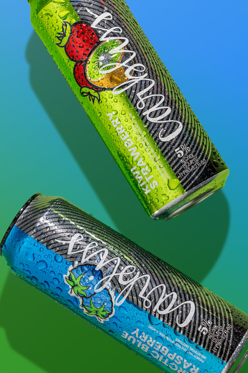 Two energy drink cans with colorful labels on a blue and green gradient background