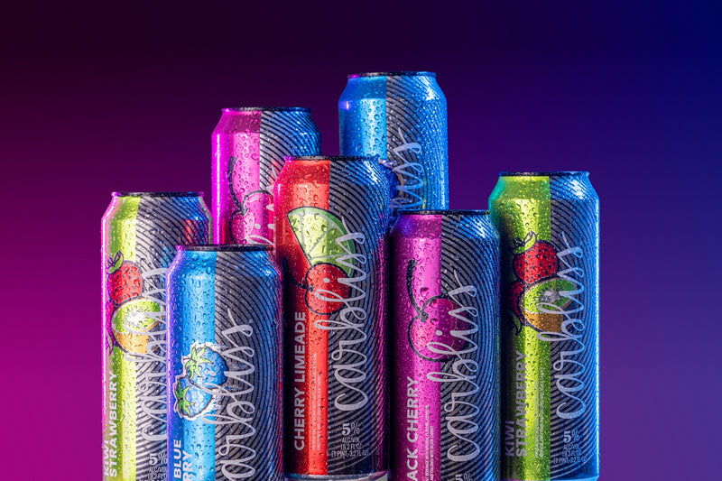 Assorted colorful soda cans on a gradient purple background