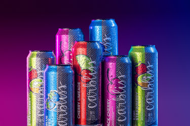 Assorted colorful soda cans on a gradient purple background