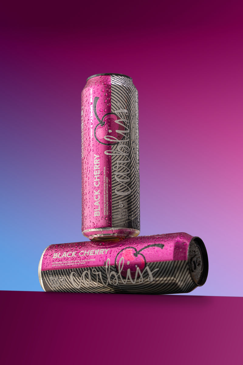 Two pink cans with black cherry branding on a gradient background