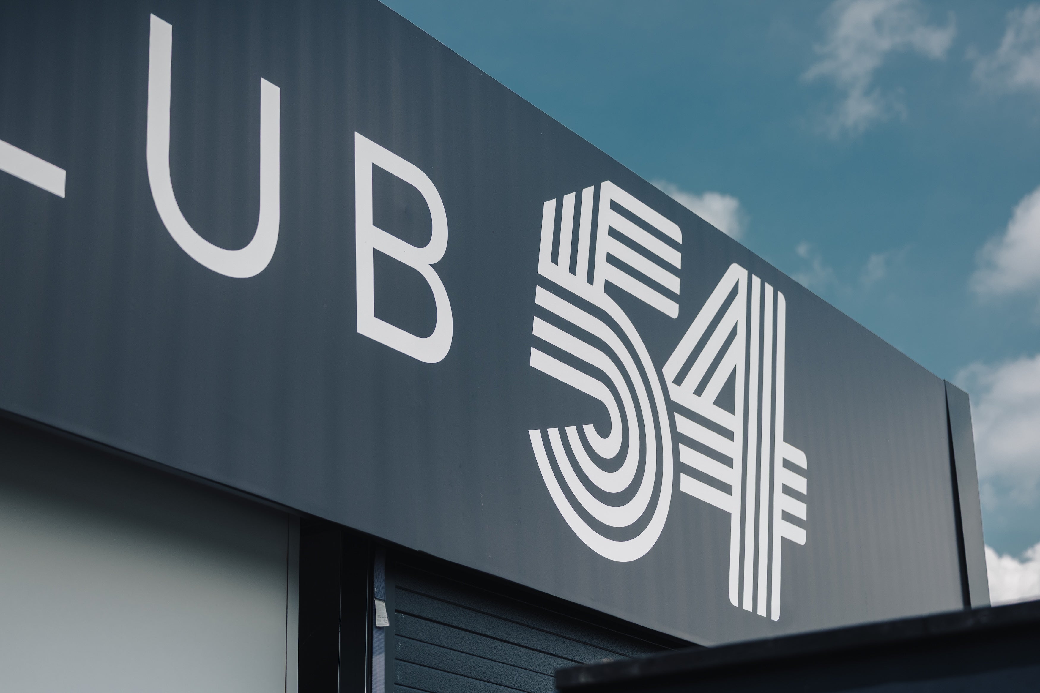 Building facade with 'CLUB 54' branding against a blue sky.