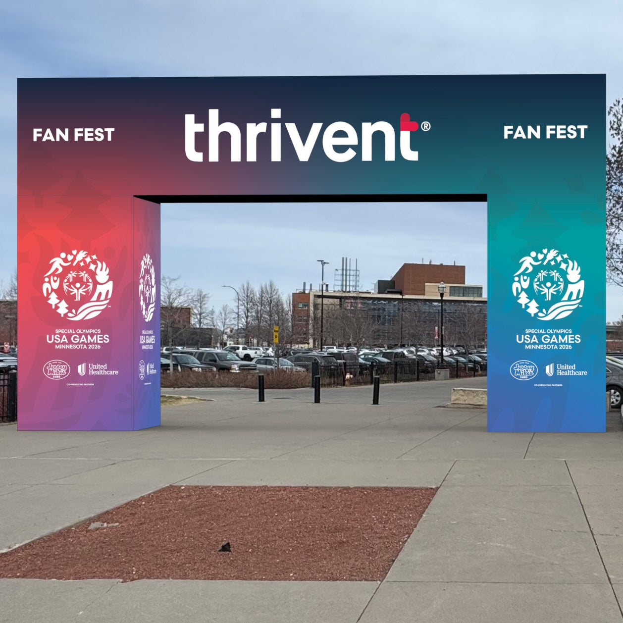 A large outdoor archway sign for Thrivent Fan Fest, with a dark top band and red-to-blue gradient left panel plus blue-to-teal gradient right panel. The words 'FAN FEST', 'thrivent', and 'FAN FEST' are visible, along with logos and text related to US Letterman and the University of Iowa.