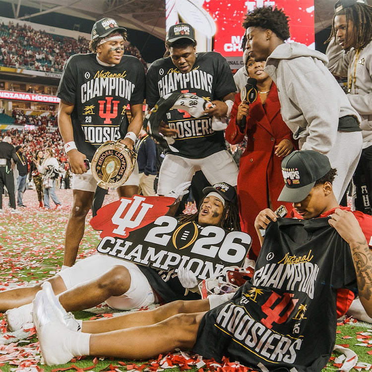 Group of people celebrating on a field with confetti, wearing 'National Champions' and '2026 Champions' shirts.