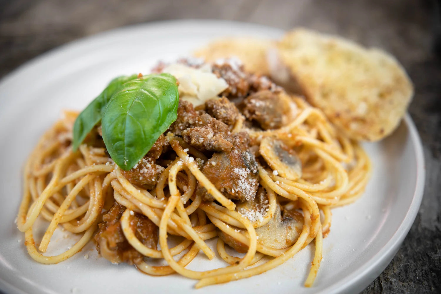 Spaghetti dish with meat sauce and basil on a white plate