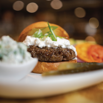Close-up of a hamburger with cheese and lettuce on a bun, blurred background