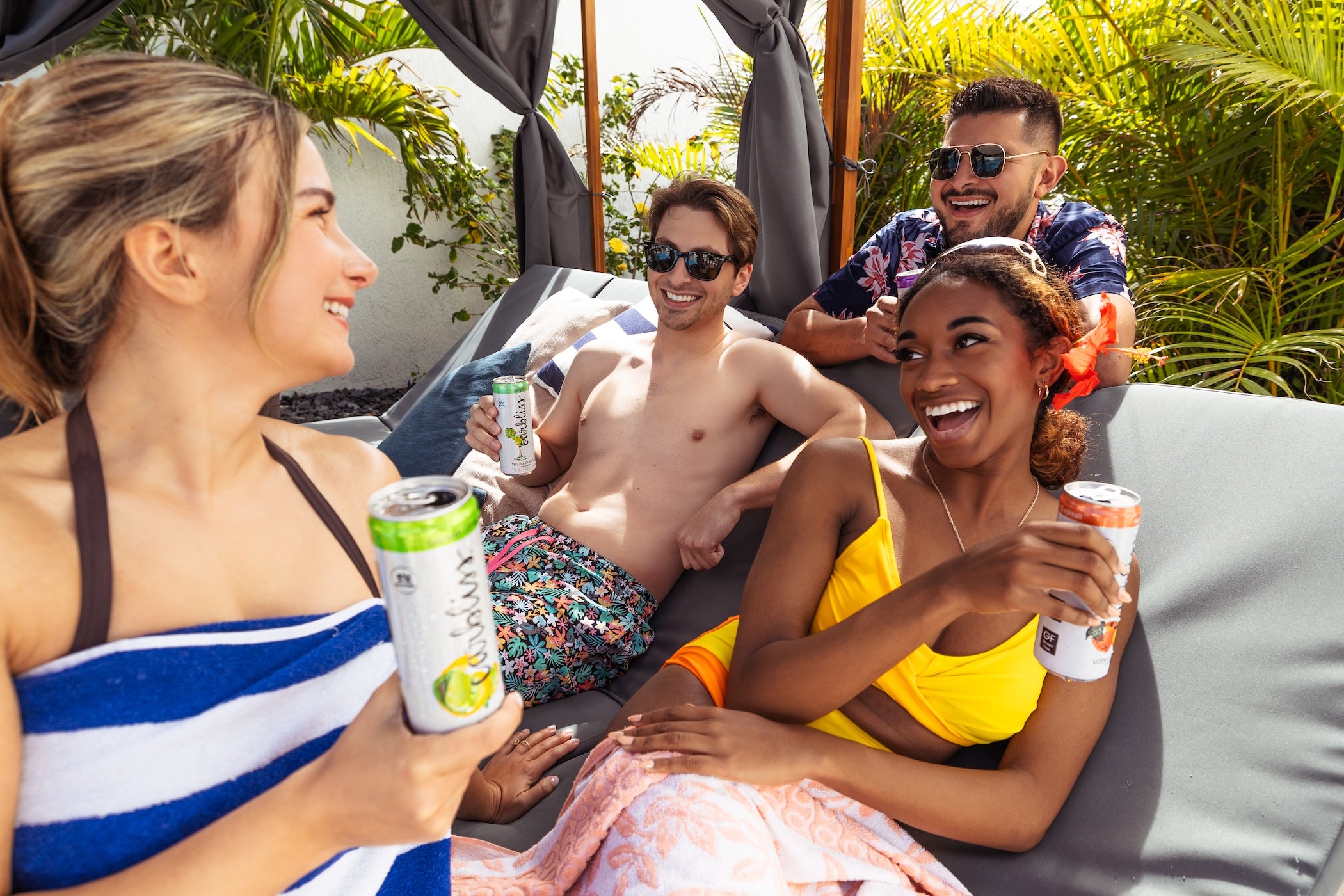 Four friends enjoying drinks and conversation on a sunny day at a resort.