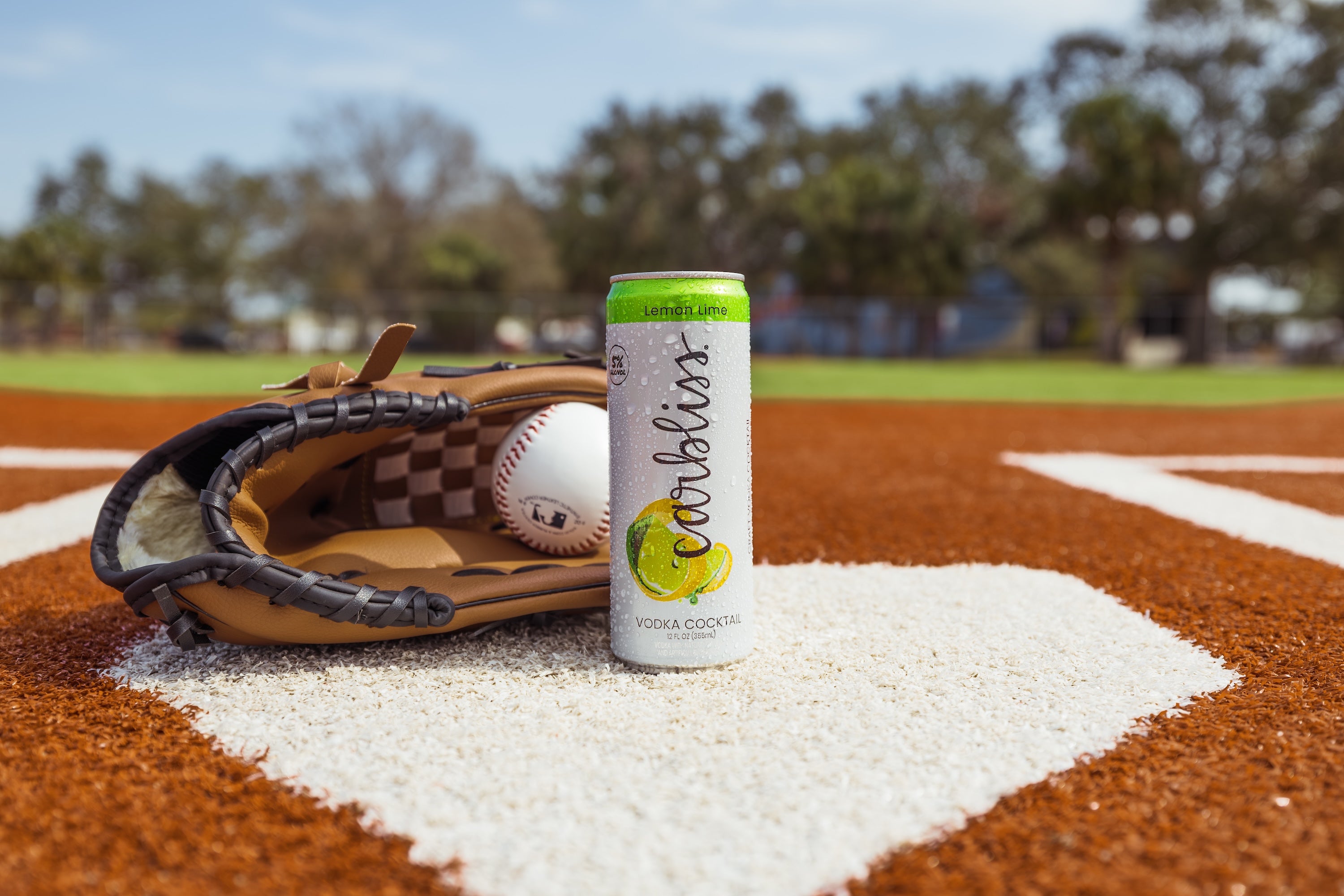 Baseball glove and can of Carbliss Lemon Lime vodka cocktail on a baseball field.