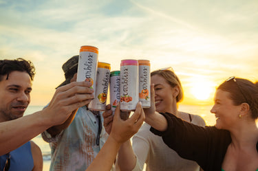 Friends cheers with Carbliss vodka cocktails at sunset on the beach.