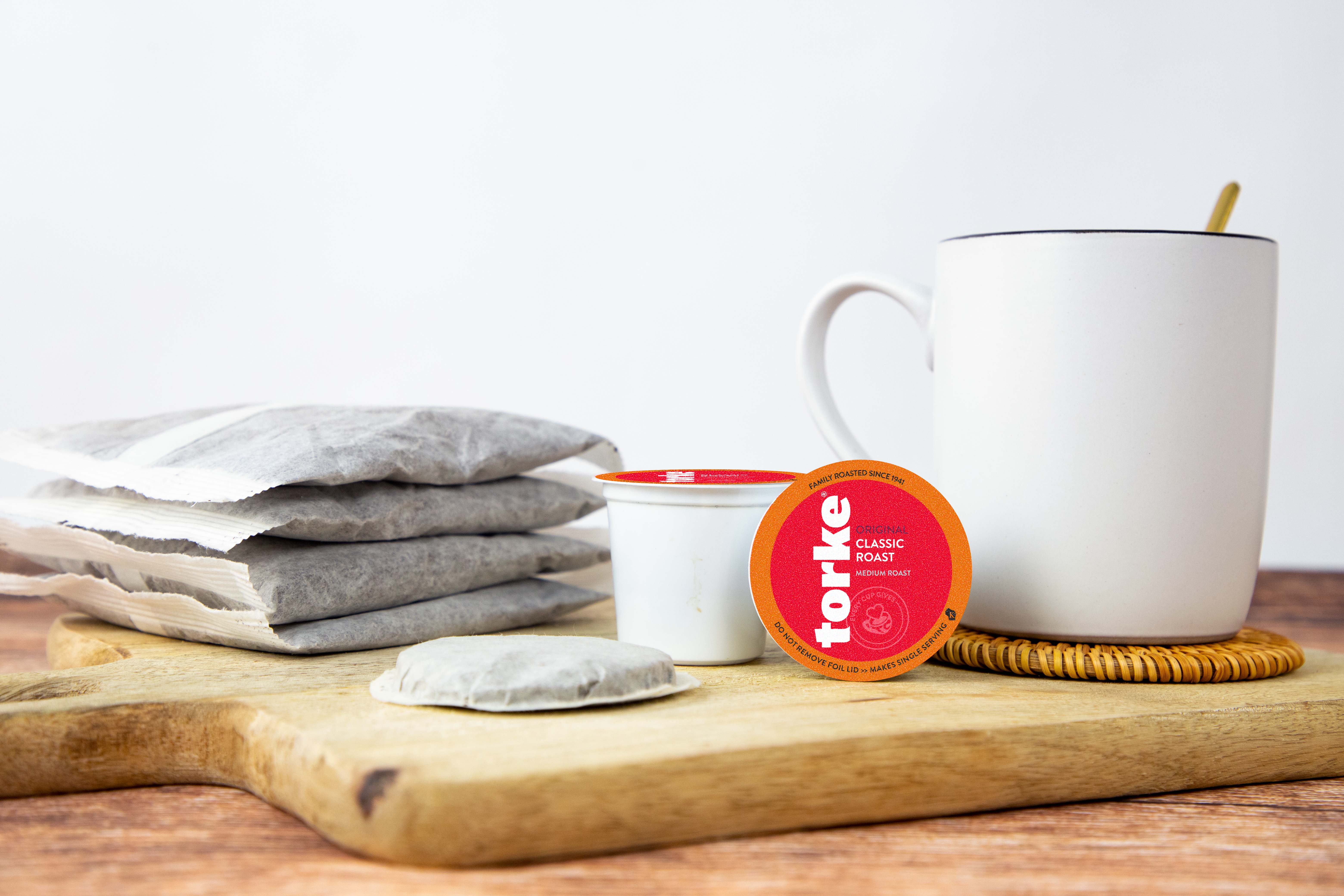 Tea bags, a mug, and a Torke tea bag on a wooden board with a white background