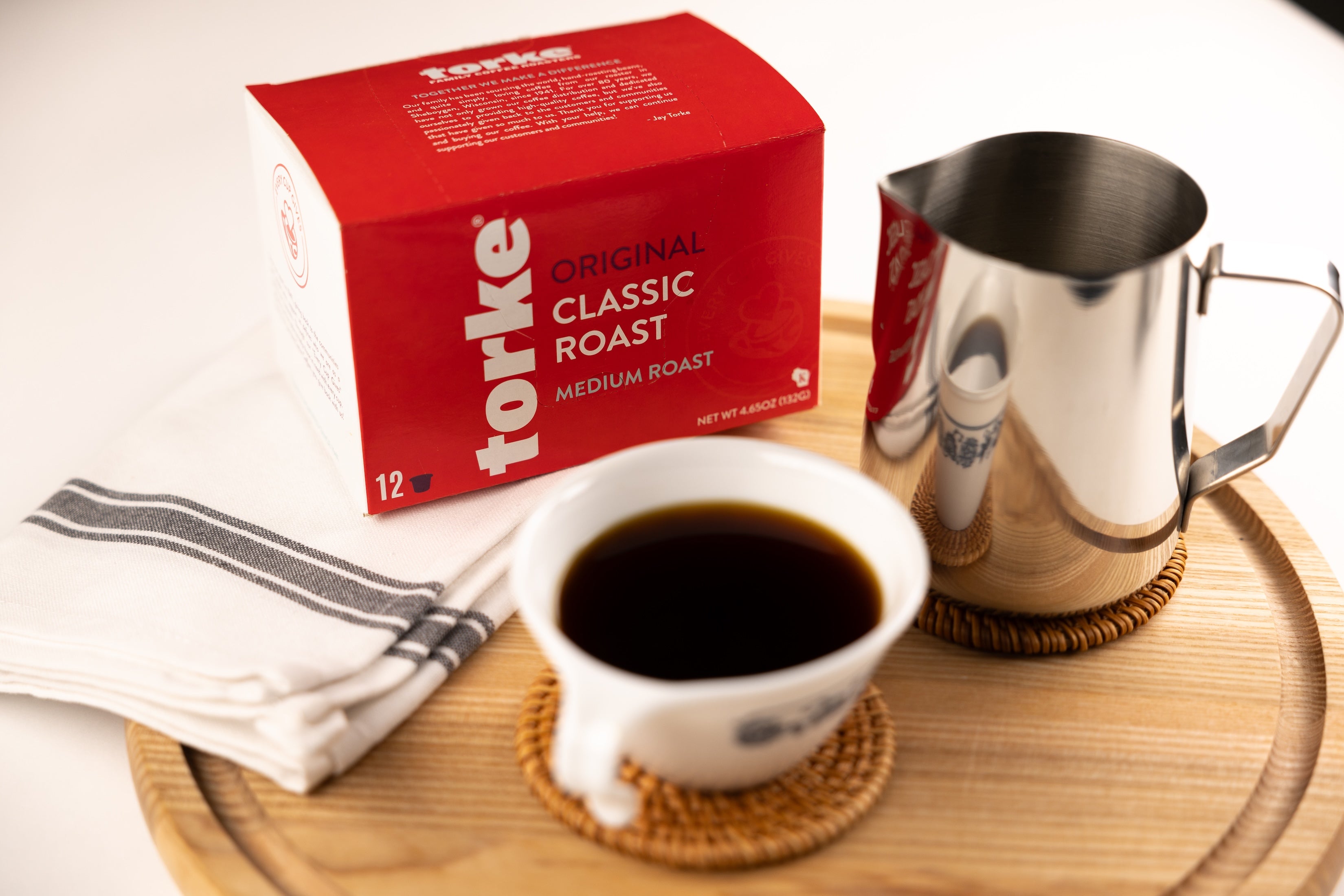 Torke coffee box with a cup of coffee and milk pitcher on a wooden tray.