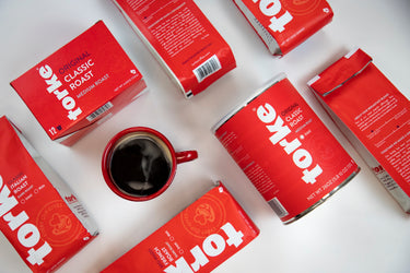 Red Torke coffee packages and a cup of coffee on a white background