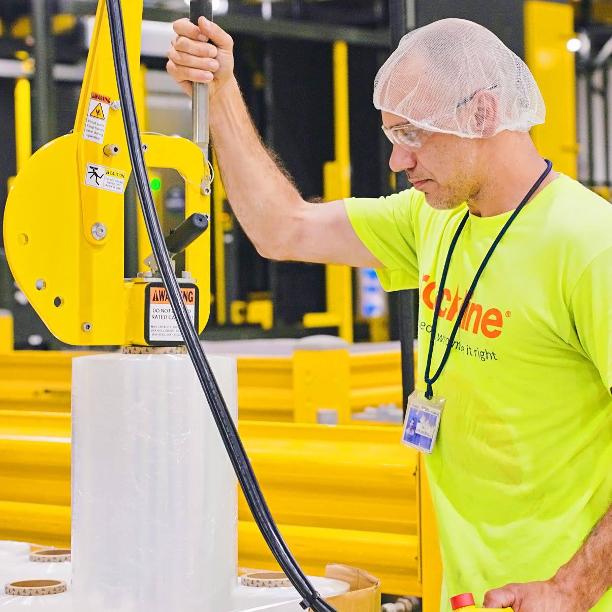 Person in a bright yellow shirt and hairnet operating machinery in an industrial setting