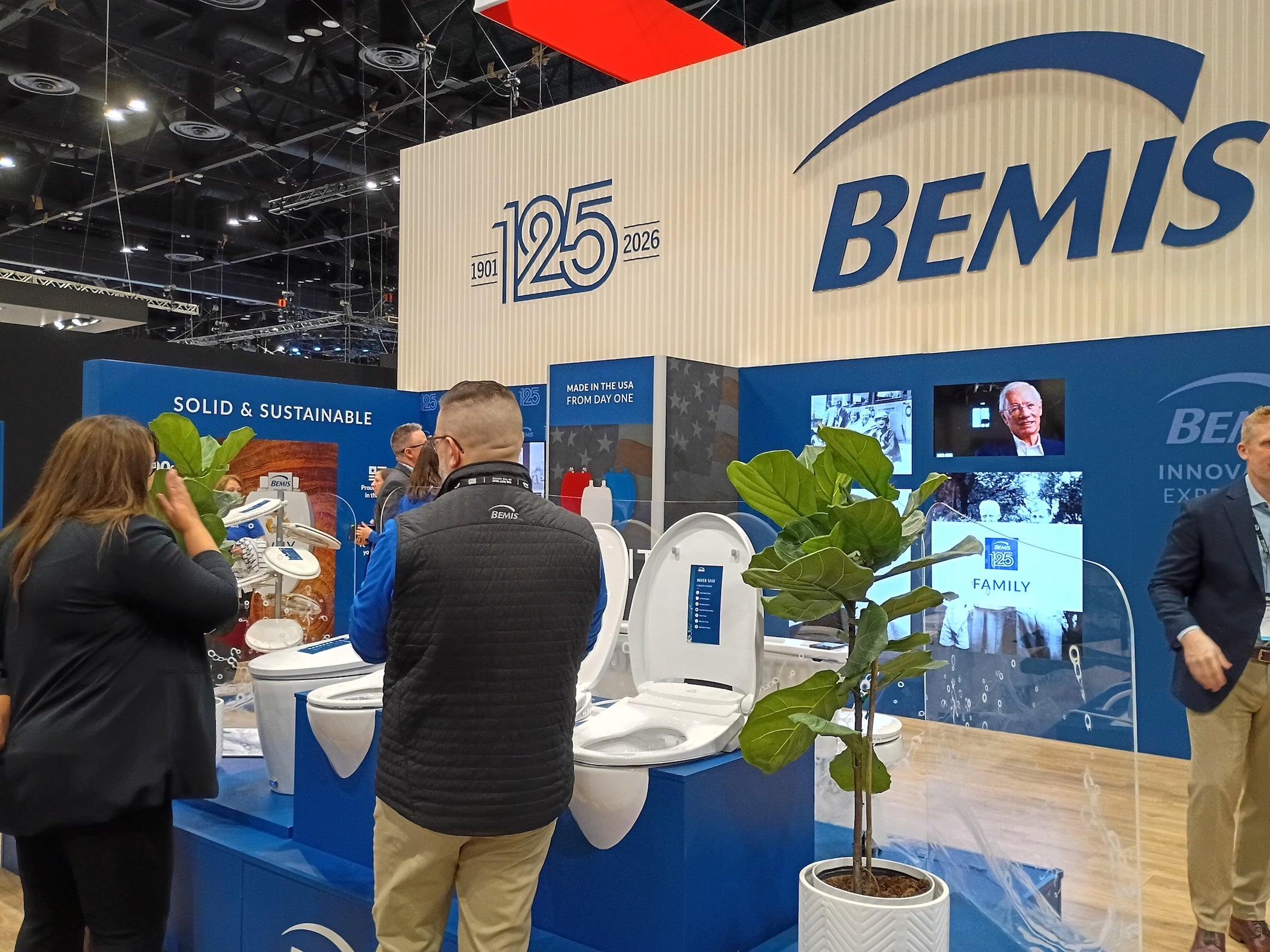 Bemis booth at a trade show with people interacting and displaying toilet products.