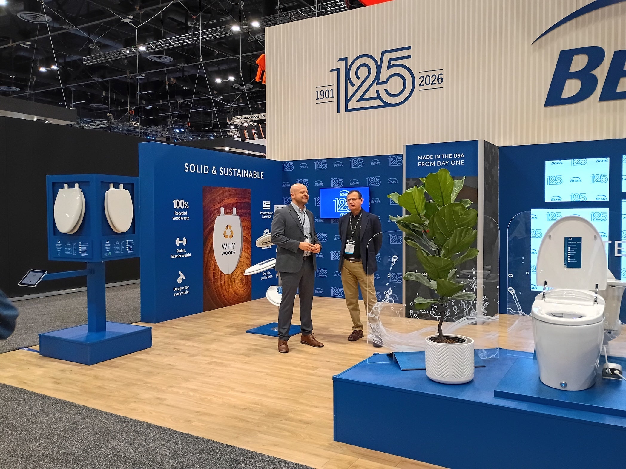 Two men standing in front of a BBW (Bemis Bradley Waterous) display at an event with '125' branding.