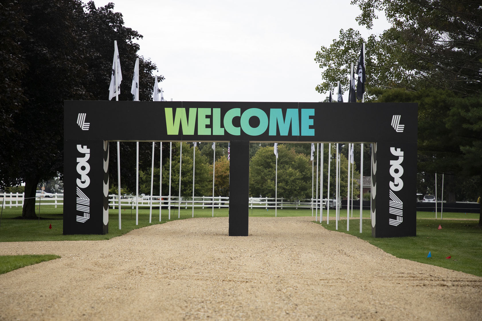 LIV Golf welcome arch with green-blue lettering over a gravel path.