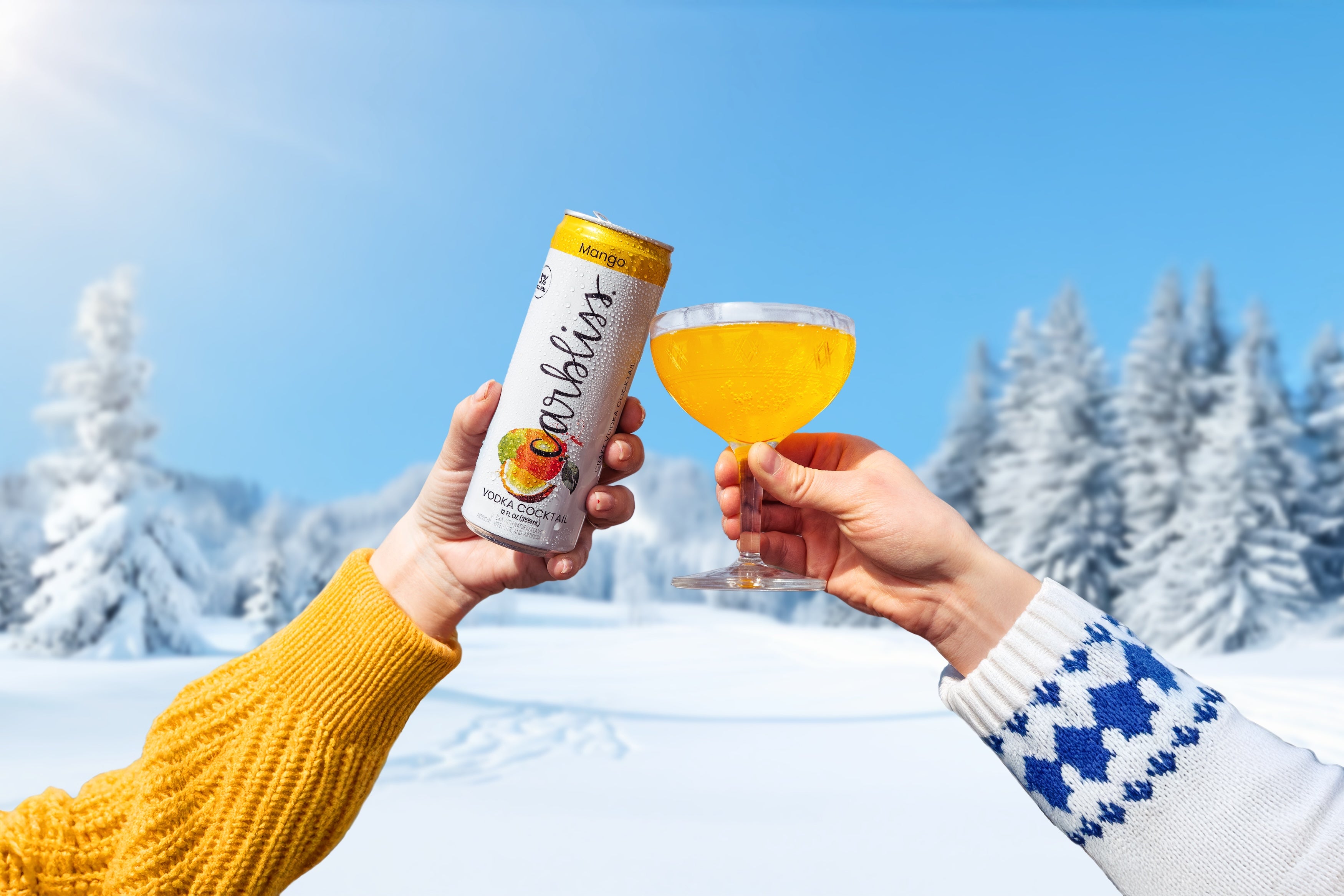 Two people holding a can of Caribou Coffee and a glass of orange juice against a snowy landscape.